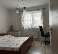 Ložnice s postelí, pracovní židlí a komodou v rodinném domě.