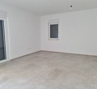 Prázdný pokoj se světlými stěnami a dlažbou ve 4pokojovém bytě.