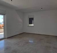 Prostorný pokoj čtyřpokojového bytu s výhledem do exteriéru přes balkónové dveře.