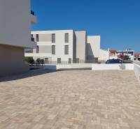 Parkoviště u 4pokojového bytu ve městě Vodice se zpevněným povrchem a čistou architekturou.
