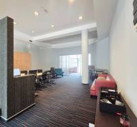 Obchodní prostory s konferenčním stolem, červenou sedačkou a moderním nábytkem.