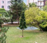 Park v Bratislavě na Československých parašutistů s lavičkou a zelení, obklopený bytovými domy.