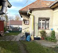 Rodinný dům na Partizánské ulici v Detvě s dvorem, rostlinami a odvodňovacími trubkami.