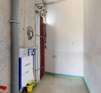 Prázdná koupelna v přízemí rodinného domu s instalacemi a potrubím.