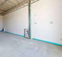 Neomítnutá místnost s instalací v rodinném domě, odkrytý strop a dveře na terasu.