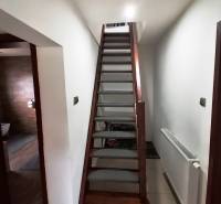 Interiér rodinného domu se schodištěm, vedle radiátor a vstup do koupelny.