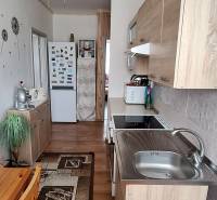 Kuchyně v 3-pokojovém bytě s dřevěným nábytkem a stropním ventilátorem.