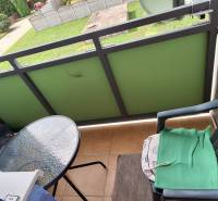 Balkon 3-pokojového bytu s plastovou židlí a malým skleněným stolkem.