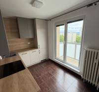 Kuchyně v 2-pokojovém bytě s dřevěnou pracovní deskou a přístupem na balkon.