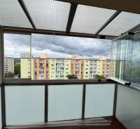 Zasklený balkon s výhledem na barevné bytovky v Nové Dubnici na ulici SNP.