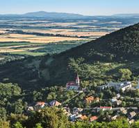 Panoramatický pohled na vesnici v údolí, obklopenou lesy a poli. Pozemky vhodné k bydlení.