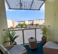 Balkon 3-pokojového bytu s ratanovým nábytkem a výhledem na sídliště v Prievidzi.