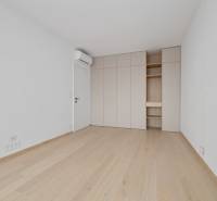 Prázdný pokoj s dřevěnou podlahou, vestavěnou skříní a klimatizací v 2-pokojovém bytě.