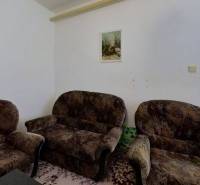 Obývací pokoj v rodinném domě se židlemi, obrazy a kobercem na podlaze.