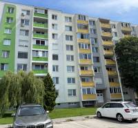 Bytový dům na Železiarenské ulici v Galantě se zaparkovanými auty a zelení.