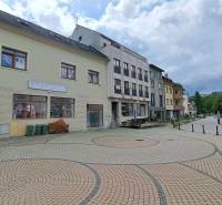Budova na Mostní ulici v Ružomberku s dlážděným náměstím a okolní infrastrukturou.