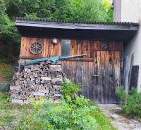 Dřevěná chata v lese na Kordících v Banské Bystrici s uloženým dřevem.