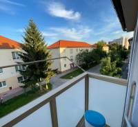 Balkon 2-pokojového bytu na Hurbanově ulici ve Skalici s výhledem na stromy a budovy.