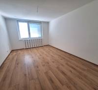Prázdná místnost s dřevěnou podlahou a velkým oknem, ve 2-pokojovém bytě.