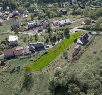 Letecký pohled na obytné pozemky v obci Raková, zelené svahy a domy.