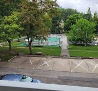 Výhled z 3pokojového bytu v Bratislavě - Ružinově na Měsíční ulici, parkoviště, stromy a hřiště.