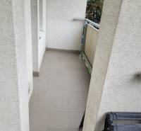 Úzký balkon v 3-pokojovém bytě se zábradlím a dlažbou.