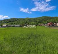 Zeleň a panorama v Udiči, pozemky - bydlení s domy a zalesněnými kopci v pozadí.