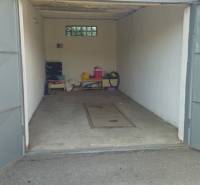 Otevřená garáž v Nové Dubnici na Topolové ulici s různými předměty a betonovou podlahou.