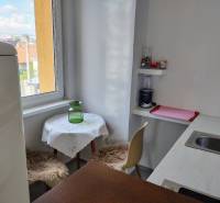Kuchyně v 2-pokojovém bytě s oknem, barovým pultem a jídelním koutem.