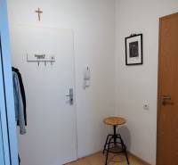 Chodba 2-pokojového bytu s věšákem, židlí a kobercem.