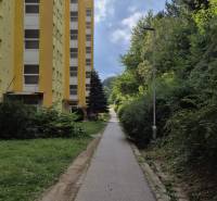 Žlutý bytový dům na Moskevské ulici v Banské Bystrici vedle chodníku a zeleně.