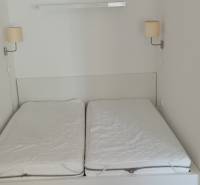 Manželská postel s lampami na stěně v 2-pokojovém bytě.