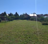 Pozemky na bydlení v Šelpiciach s travnatou plochou, obklopené domy a vegetací.