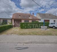 Rodinný dům v Častkovcích se zahradou, autem a studnou, obklopený zelení a chodníkem.