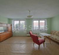 Pokoj v rodinném domě s konferenčním stolkem, sedačkou a příborníkem. Podlaha s dřevěným dekorem.