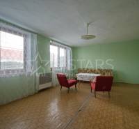 Pokoj se dvěma červenými křesly, stolem a zelenými stěnami v rodinném domě.