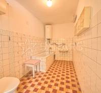 Koupelna s bílými obklady v rodinném domě, šachovnicová podlaha.