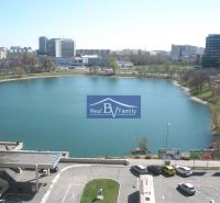 Pohled na jezero v Bratislavě - Ružinov s budovami, auty a billboardy na Drieňové ulici.