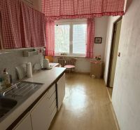 Kuchyně ve 3-pokojovém bytě se závěsy a podlahou s dřevěným dekorem.