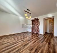 Obývací pokoj v 3-pokojovém bytě s podlahou s dřevěným dekorem a cihlovou stěnou.