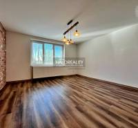 Pokoj ve 3-pokojovém bytě s podlahou s dřevěným dekorem a cihlovým obkladem na stěně.