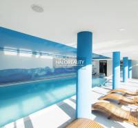 Interiérová relaxační zóna s bazénem a lehátky v gastro prostorech.