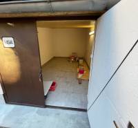 Interiér garáže s otevřenými dveřmi, podlaha s dřevěným dekorem, úložný prostor.