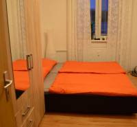 Ložnice v 2-pokojovém bytě s postelí, šatníkem a podlahou s dřevěným dekorem.