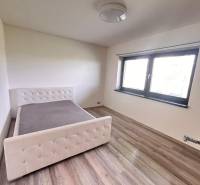 Ložnice v rodinném domě s postelí a podlahou s dřevěným dekorem.