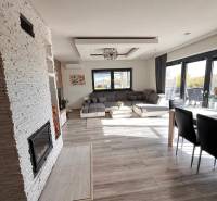 Interiér rodinného domu s pohovkou, krbem a podlahou s dřevěným dekorem.