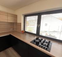 Kuchyně s dřevěným dekorem a pultem v rodinném domě, s oknem a plynovým vařičem.