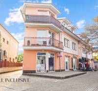 Budova na Kukučínově ulici v Dunajské Stredě se světle oranžovou fasádou a obchody.