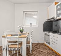 Kuchyně v 2pokojovém bytě s jídelním stolem a podlahou s dřevěným dekorem.