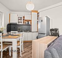 Kuchyně v 2pokojovém bytě s podlahou s dřevěným dekorem a jídelním stolem.